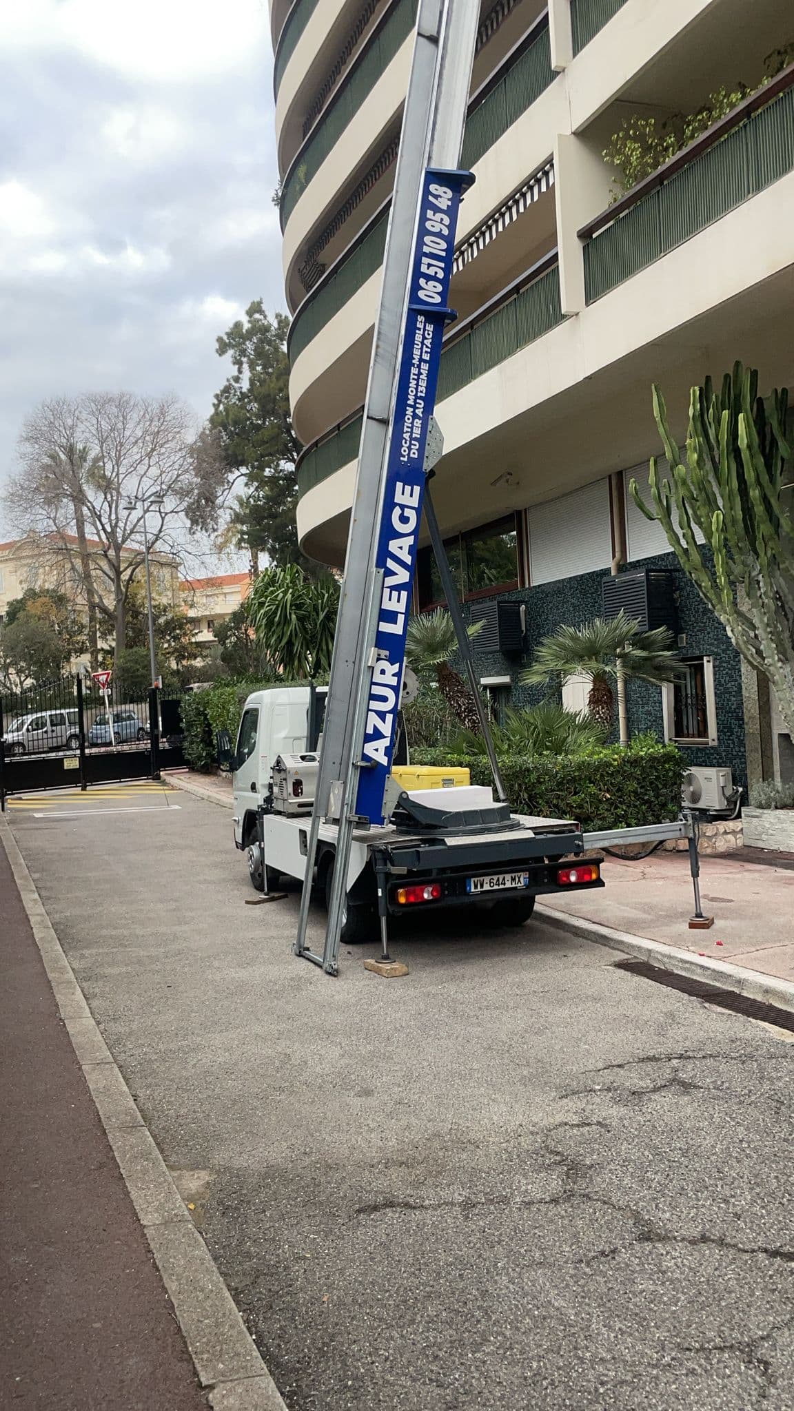 Camion monte-meuble vu de l'arriere avec echelle deployee le long d'un immeuble pour un demenagement en etage