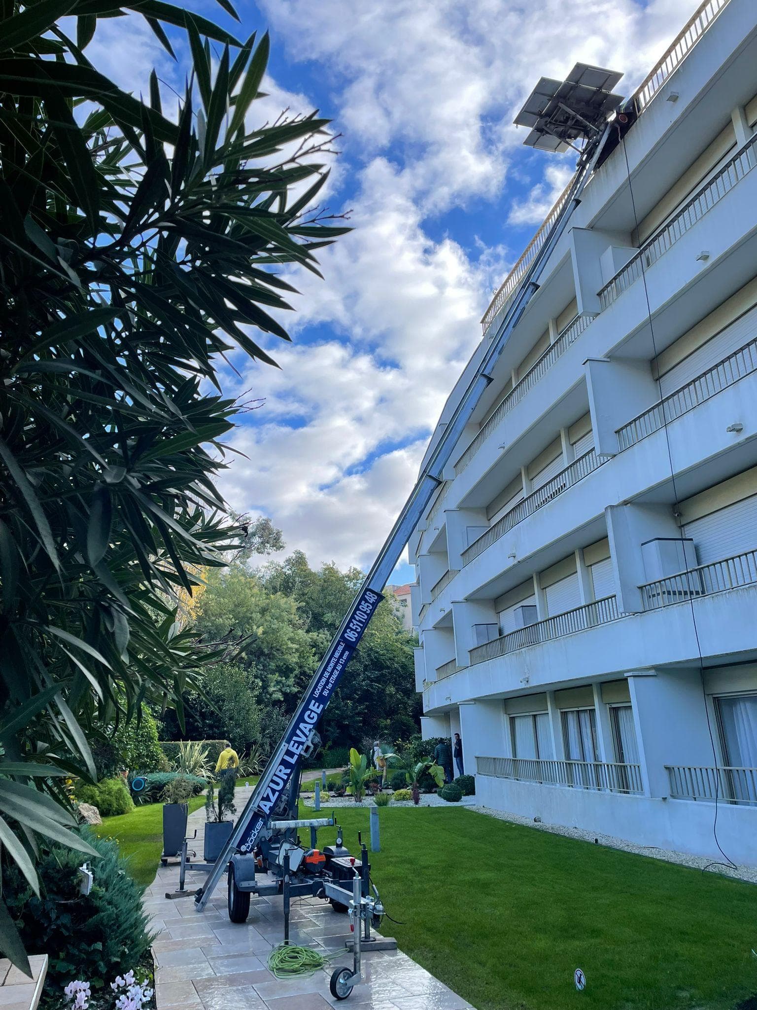 Monte-meuble en action le long d'une residence pour un demenagement en etage eleve, plateforme chargee a hauteur d'un balcon